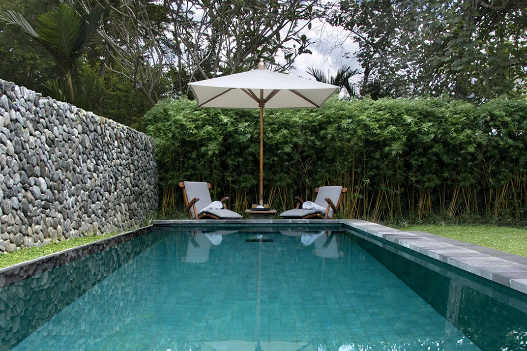 A private villa pool at Alila Ubud, enclosed by a river-stone wall and bamboo