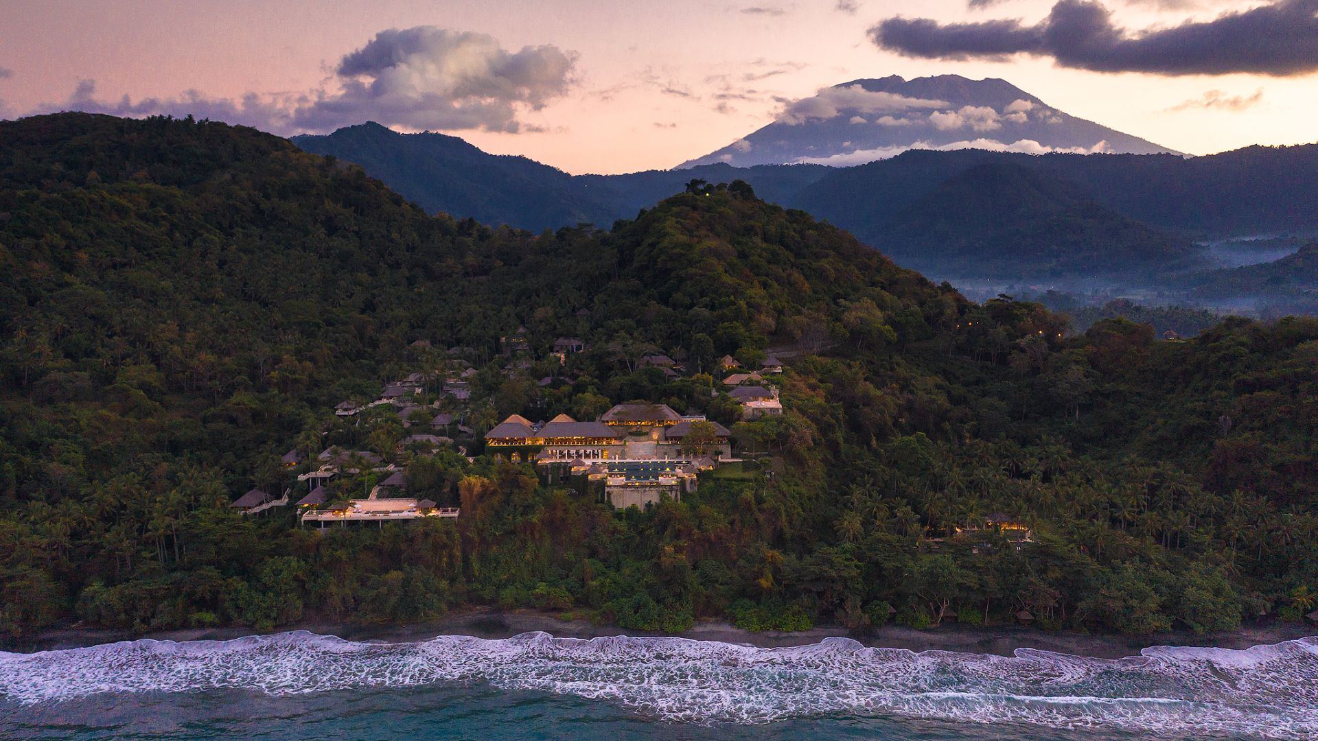Aerial view of Amankila at dusk, cut into the hillside above the Lombok Strait with Mount Agung behind