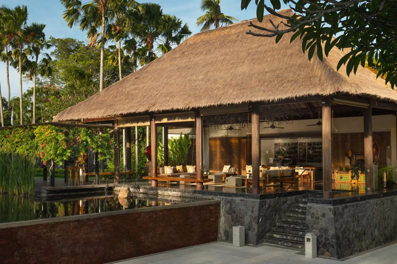 The open lobby pavilion at Amarterra, its thatched roof above red-brick walls and a reflecting pool