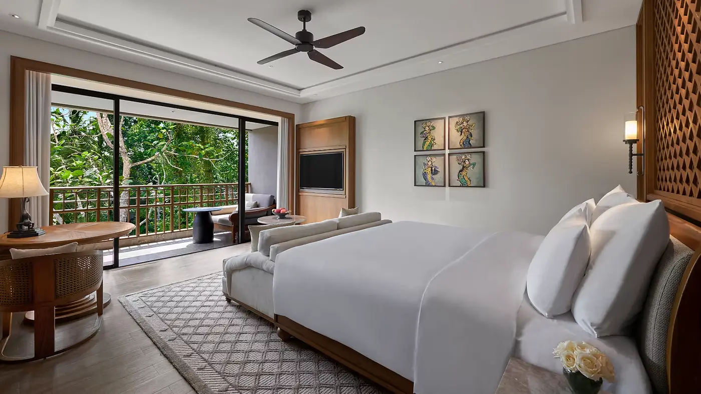 A suite bedroom at Anantara Ubud, opening onto a balcony over the treeline