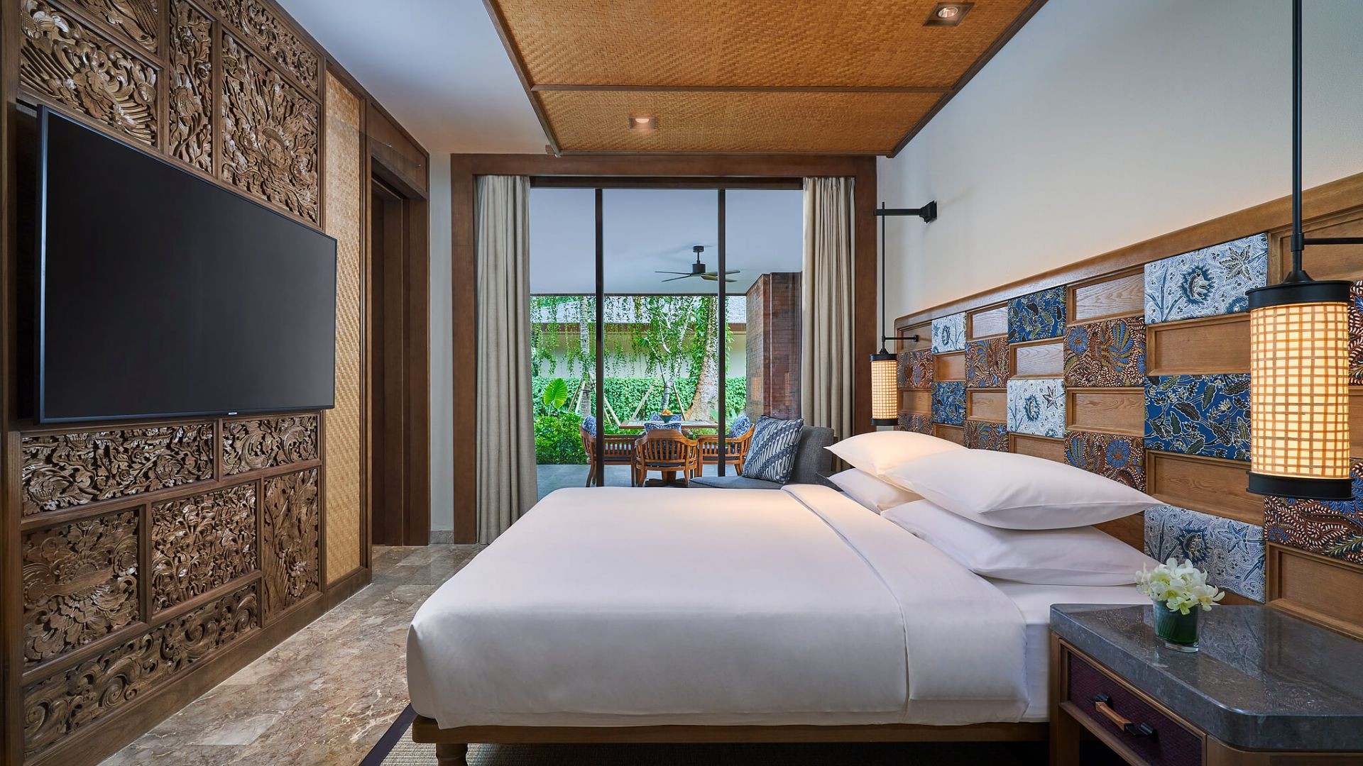 A bedroom at Andaz Bali with carved wood panelling and batik tile detailing