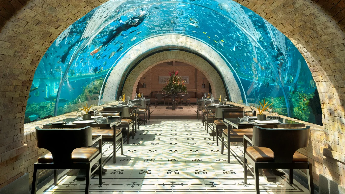 Koral, the underwater aquarium restaurant at The Apurva Kempinski Bali, tables set beneath the reef tank