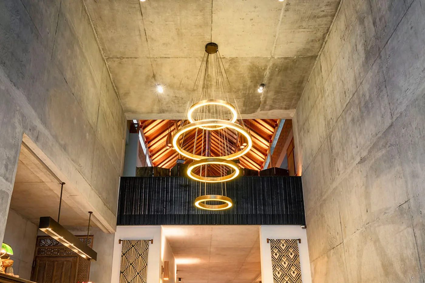 The concrete arrival hall at Bisma Eight, with rings of light above a teak reception desk