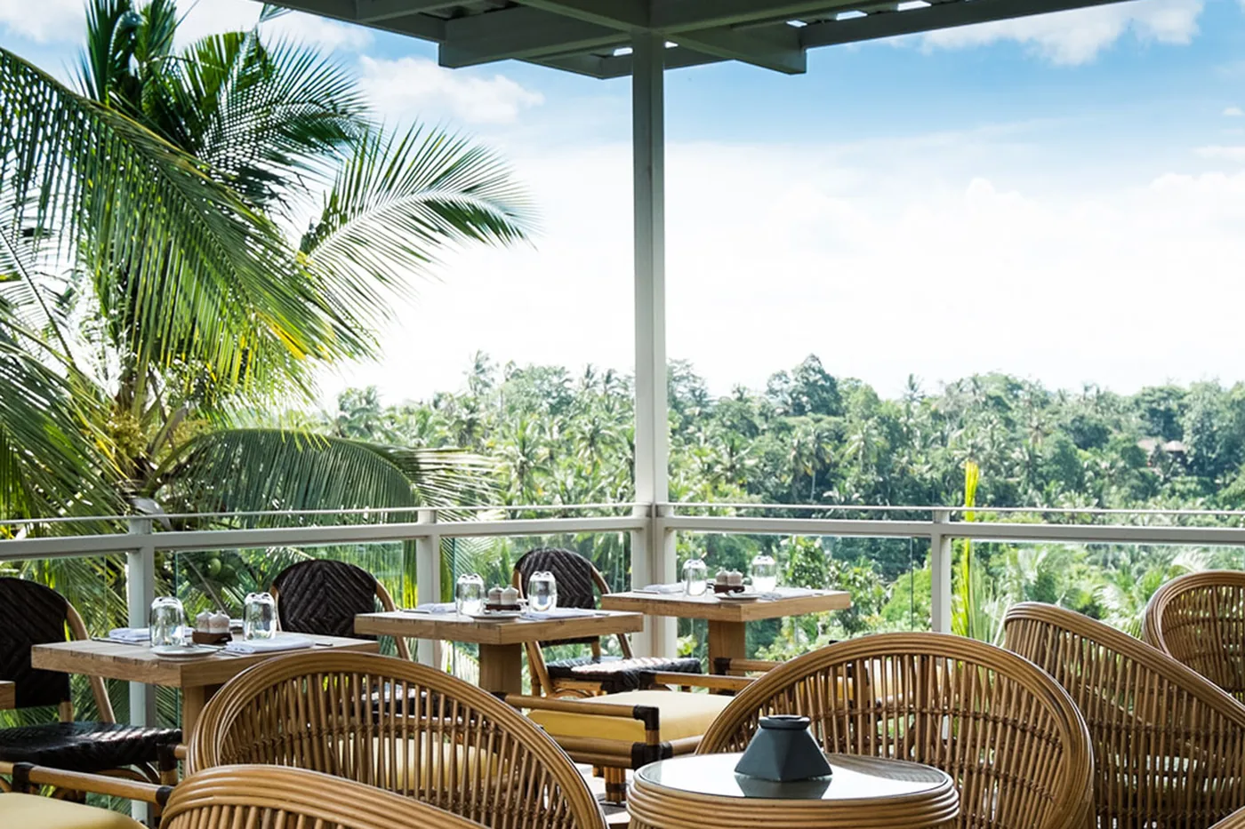 Rattan chairs on a terrace at Bisma Eight looking into the palms of the Campuhan valley