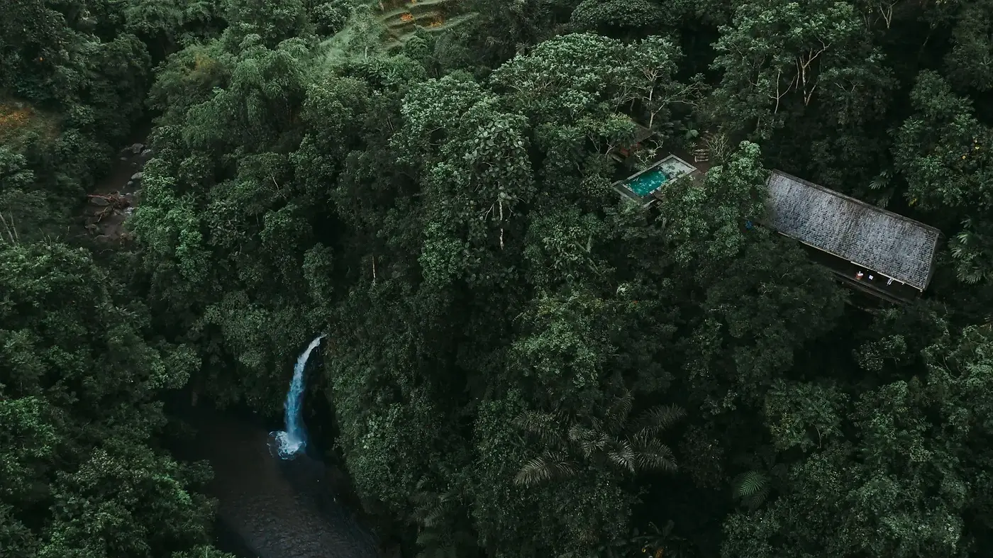 An aerial view of a Buahan balé and plunge pool set above a jungle waterfall in the Ayung valley