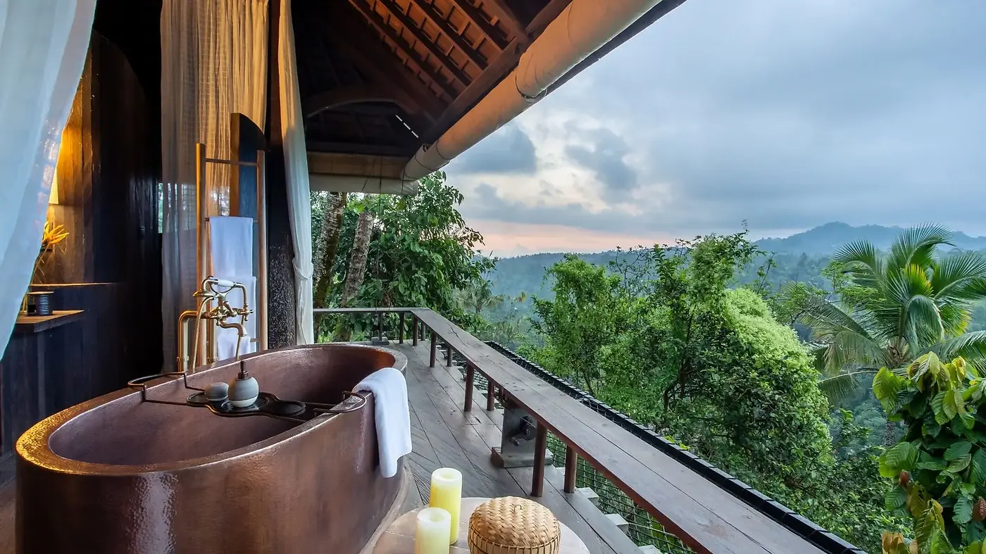 A hand-smithed copper bathtub on a balé deck at Buahan, overlooking the jungle at dusk