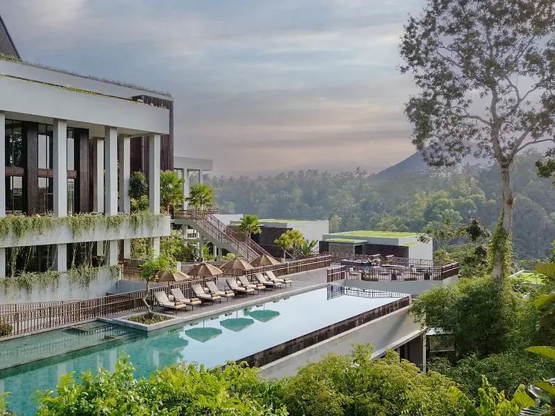 Anantara Ubud perched on its hillside, the infinity pool running along the building with Mount Agung behind
