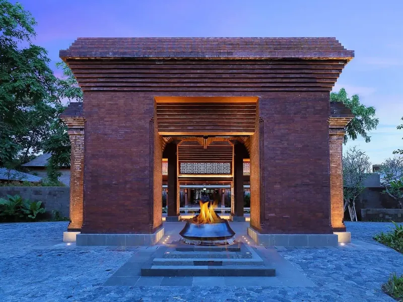 Andaz Bali's red brick entrance gate in Sanur, lit at dusk