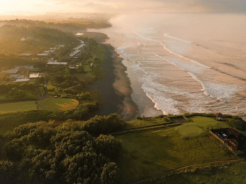 Soori Bali's coastline at dawn, mist over black volcanic sand