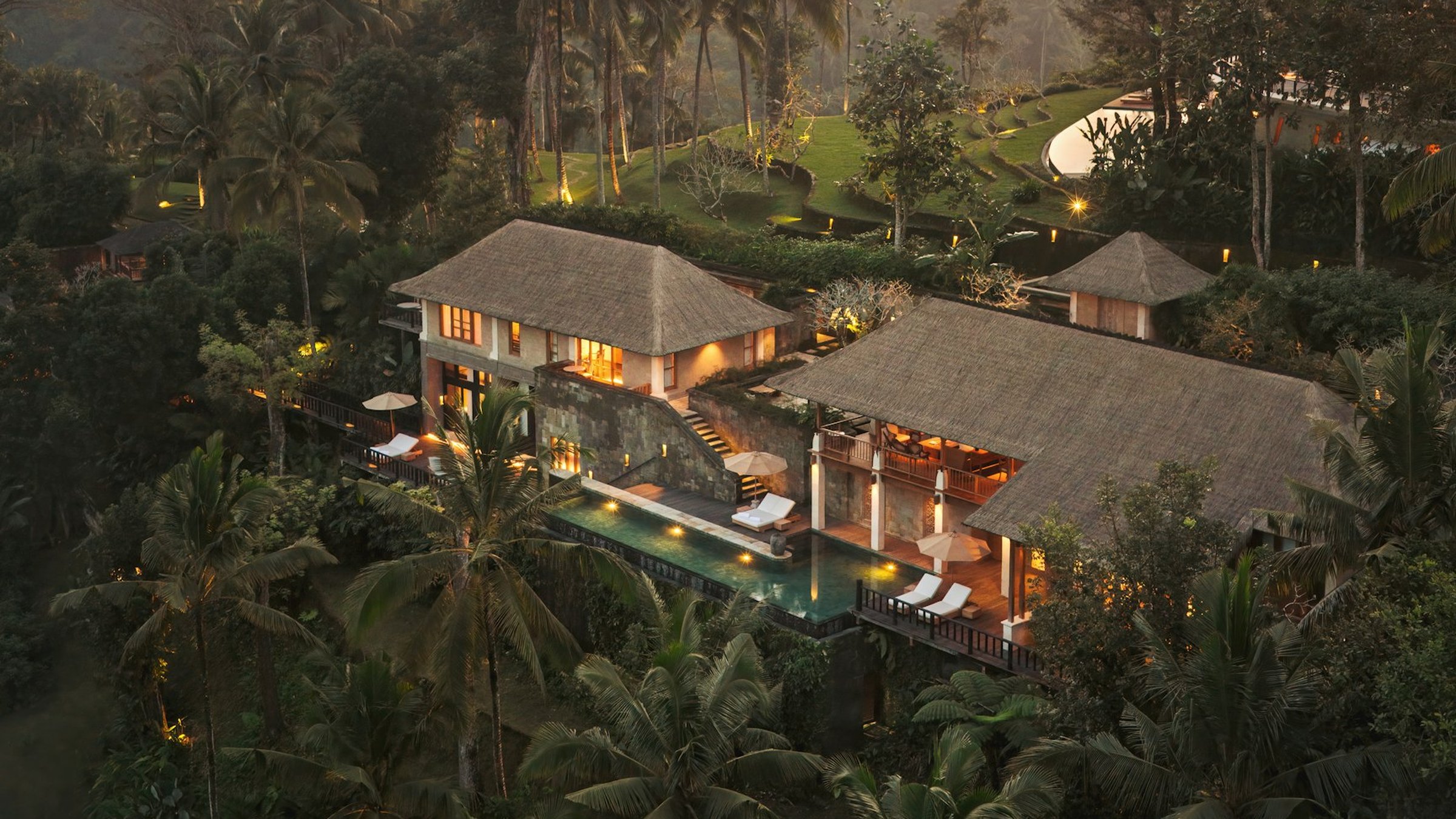 Aerial view of a Residence at Como Shambhala Estate at dusk, lit up amid the jungle