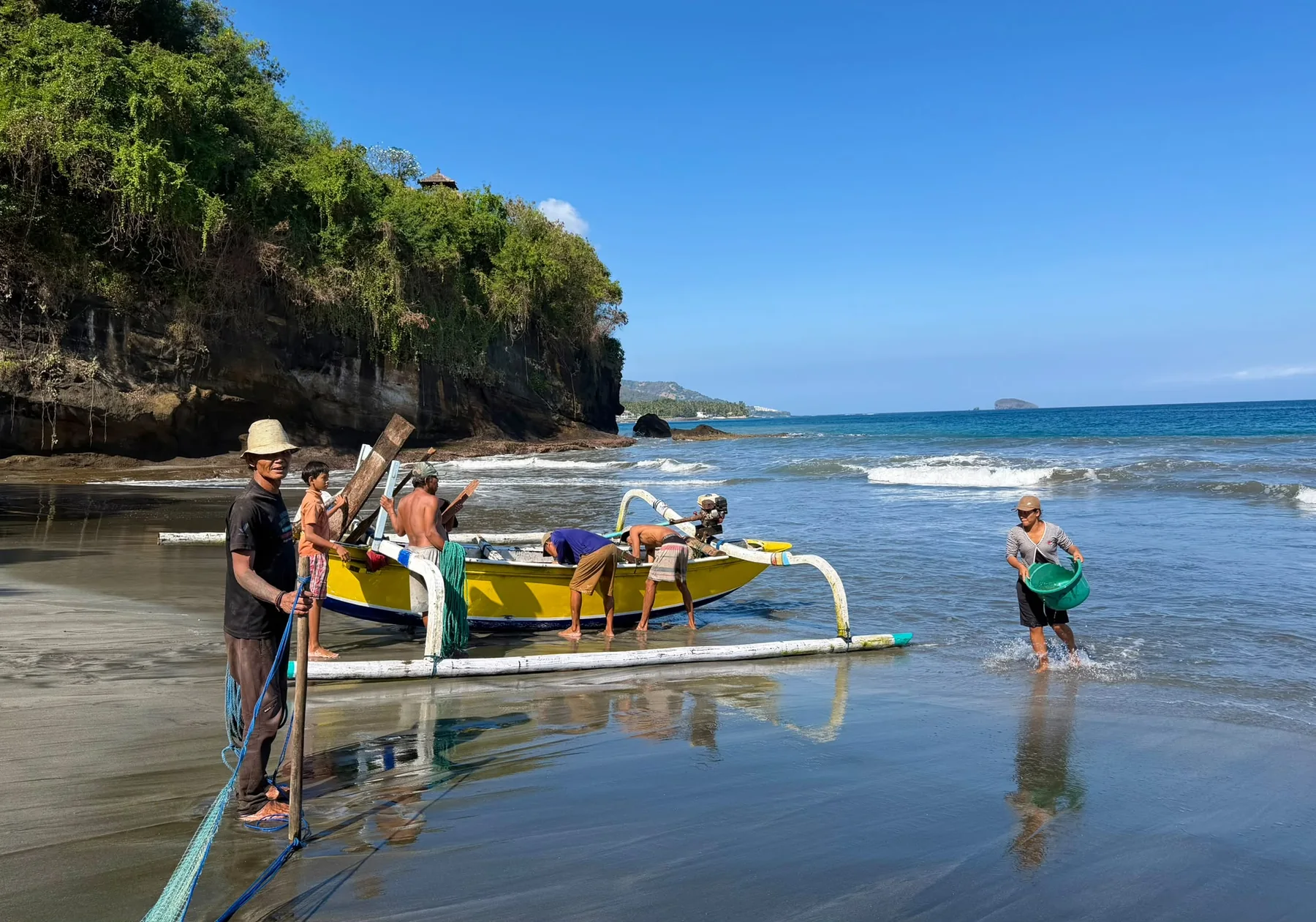 Fishermen pushing a traditional jukung out through the surf in east Bali