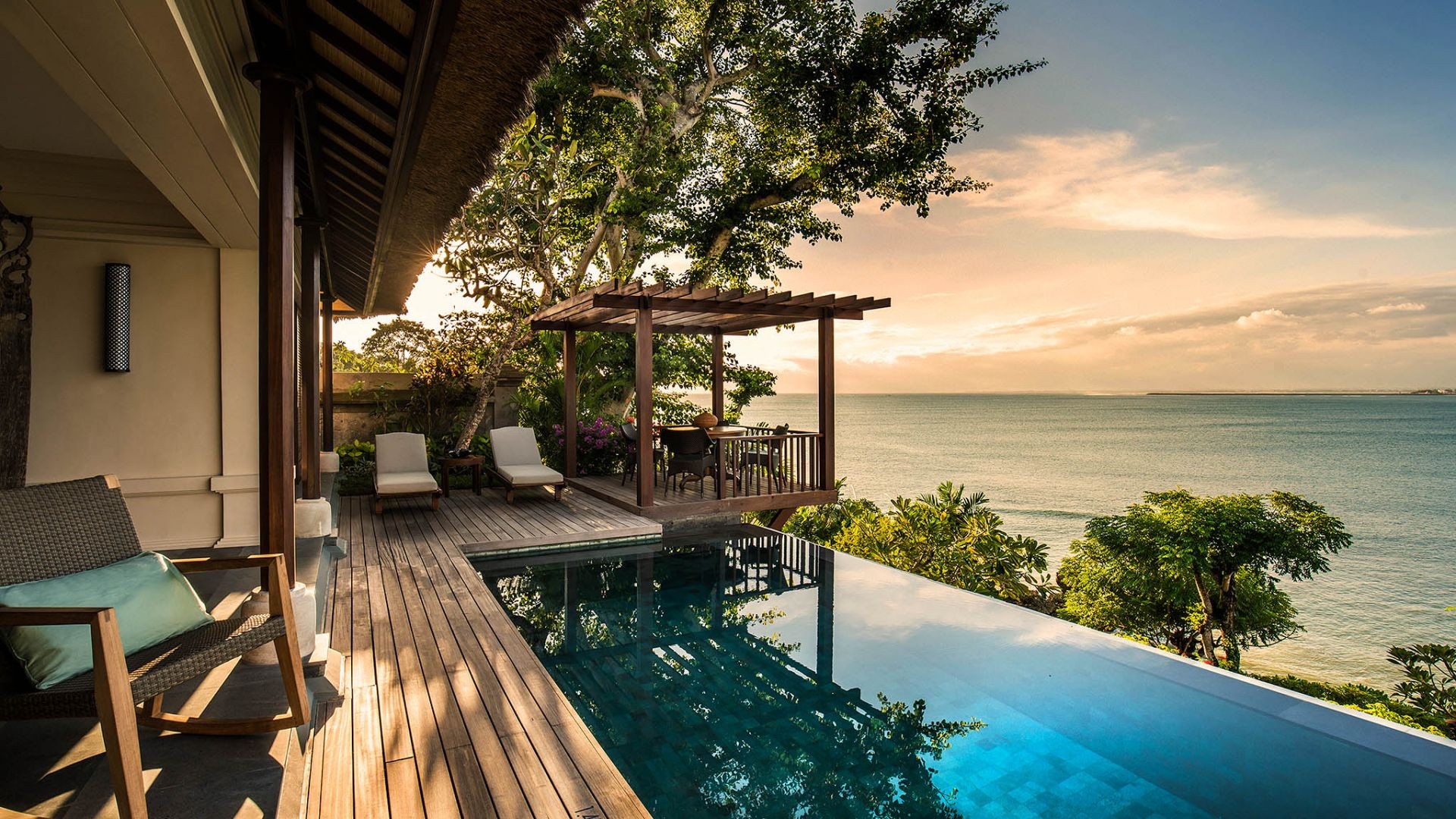 A villa terrace and infinity pool at Four Seasons Resort Bali at Jimbaran Bay at sunset, overlooking the ocean