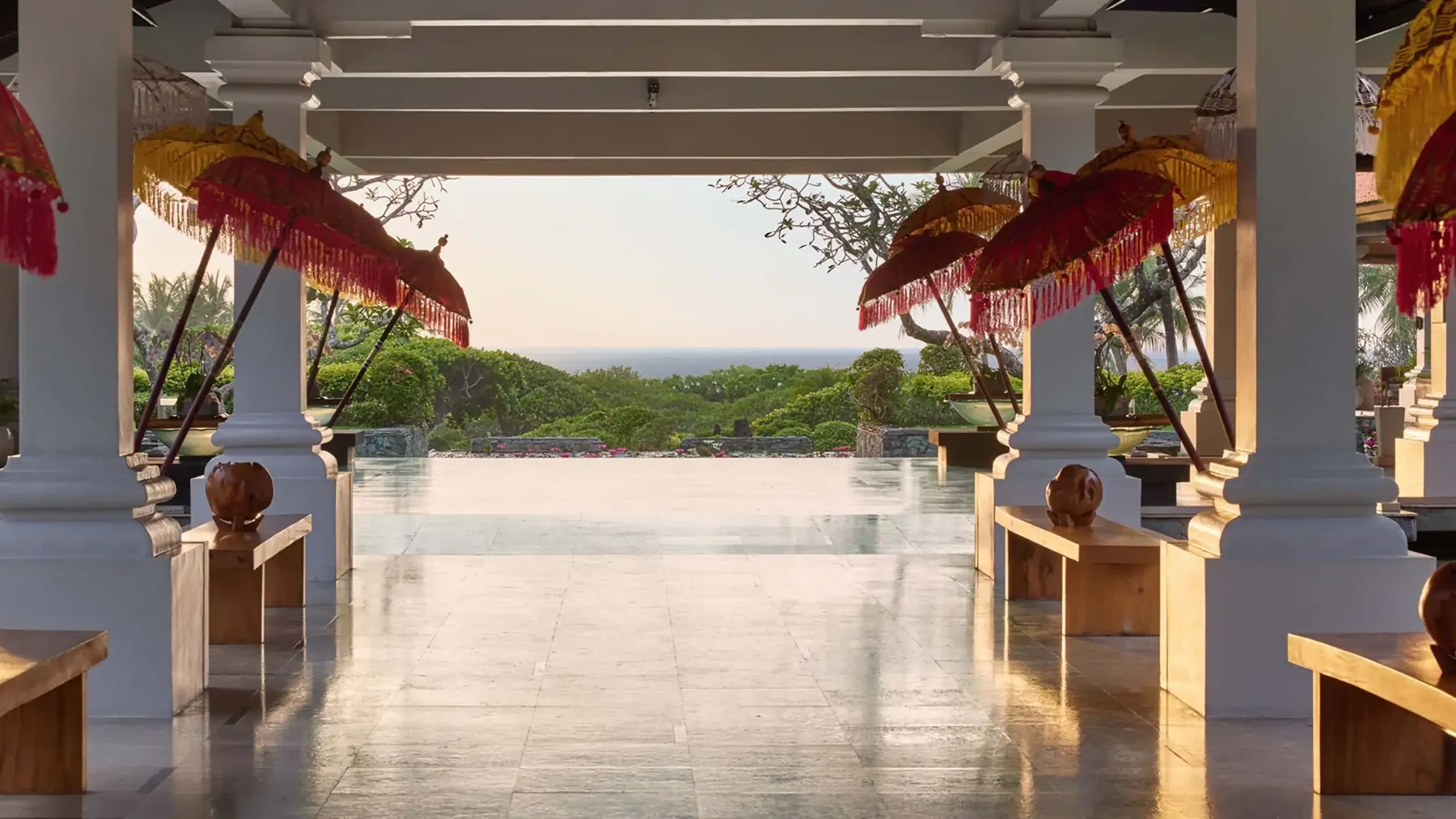 A colonnade at Grand Hyatt Bali hung with Balinese ceremonial parasols, looking out to the sea