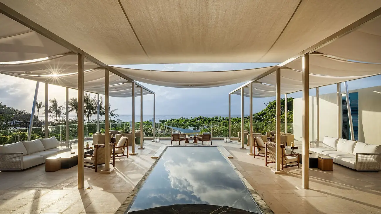 A shaded lounge deck at InterContinental Bali Sanur with a reflecting pool and ocean view