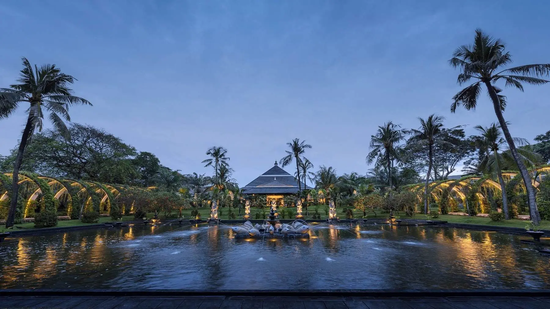 The fountain court at the InterContinental in Jimbaran at dusk, lit arches either side