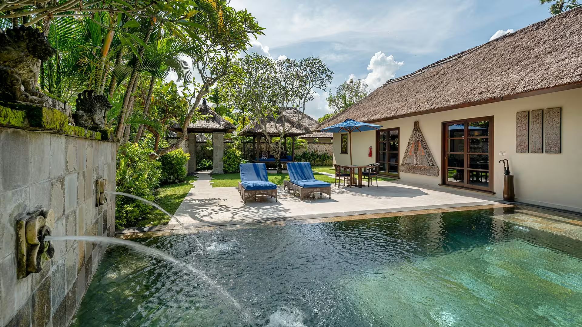 A private pool villa at Jimbaran Puri, with sun loungers, a blue umbrella, and a plunge pool