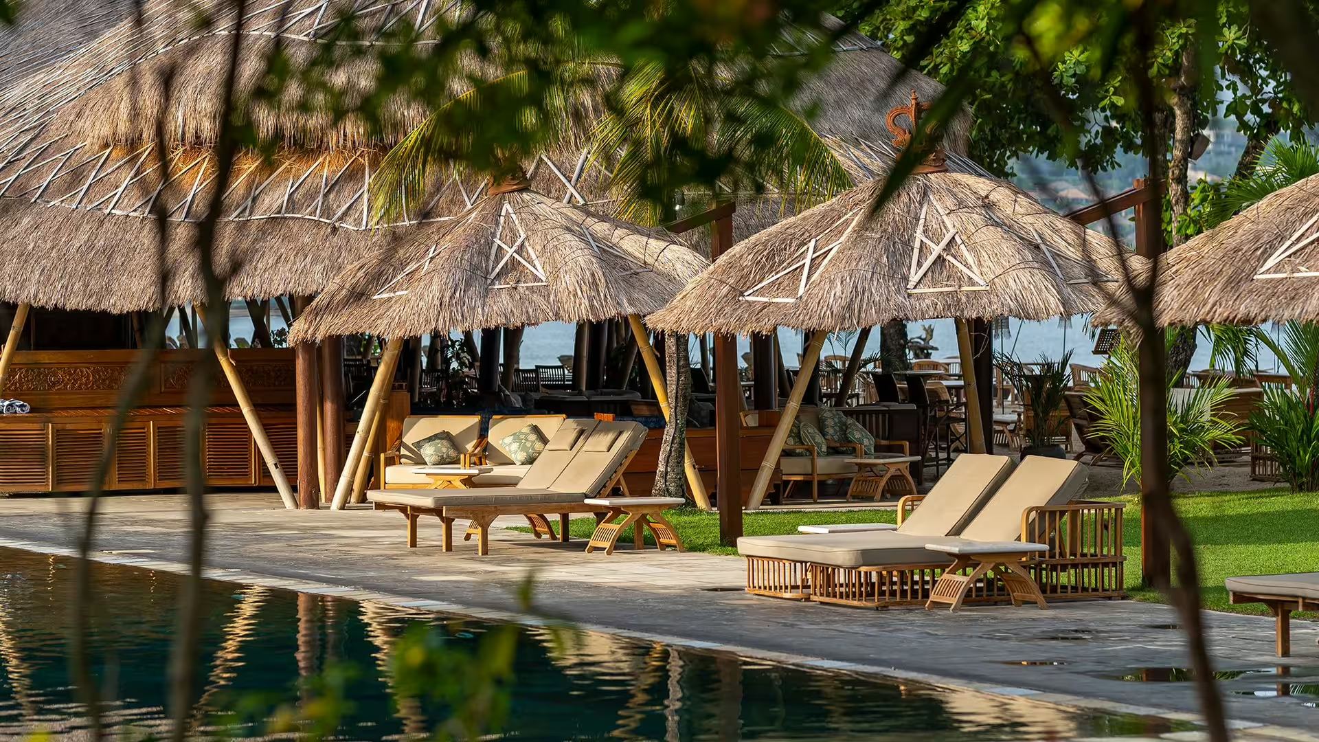 Thatched loungers and a bar beside the pool at Jimbaran Puri