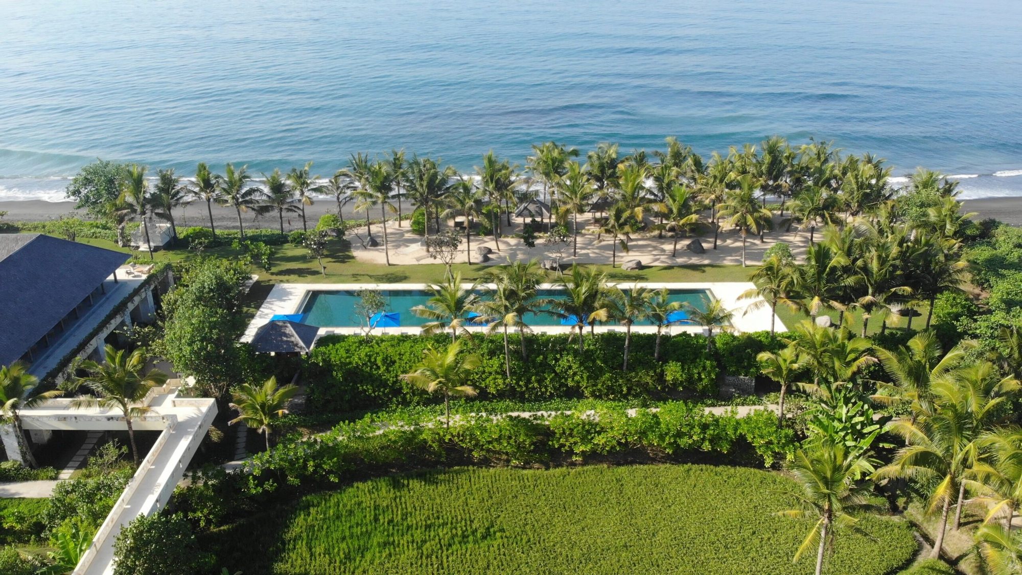 Aerial view of Komaneka at Keramas Beach, its pool, black sand beach and living rice fields