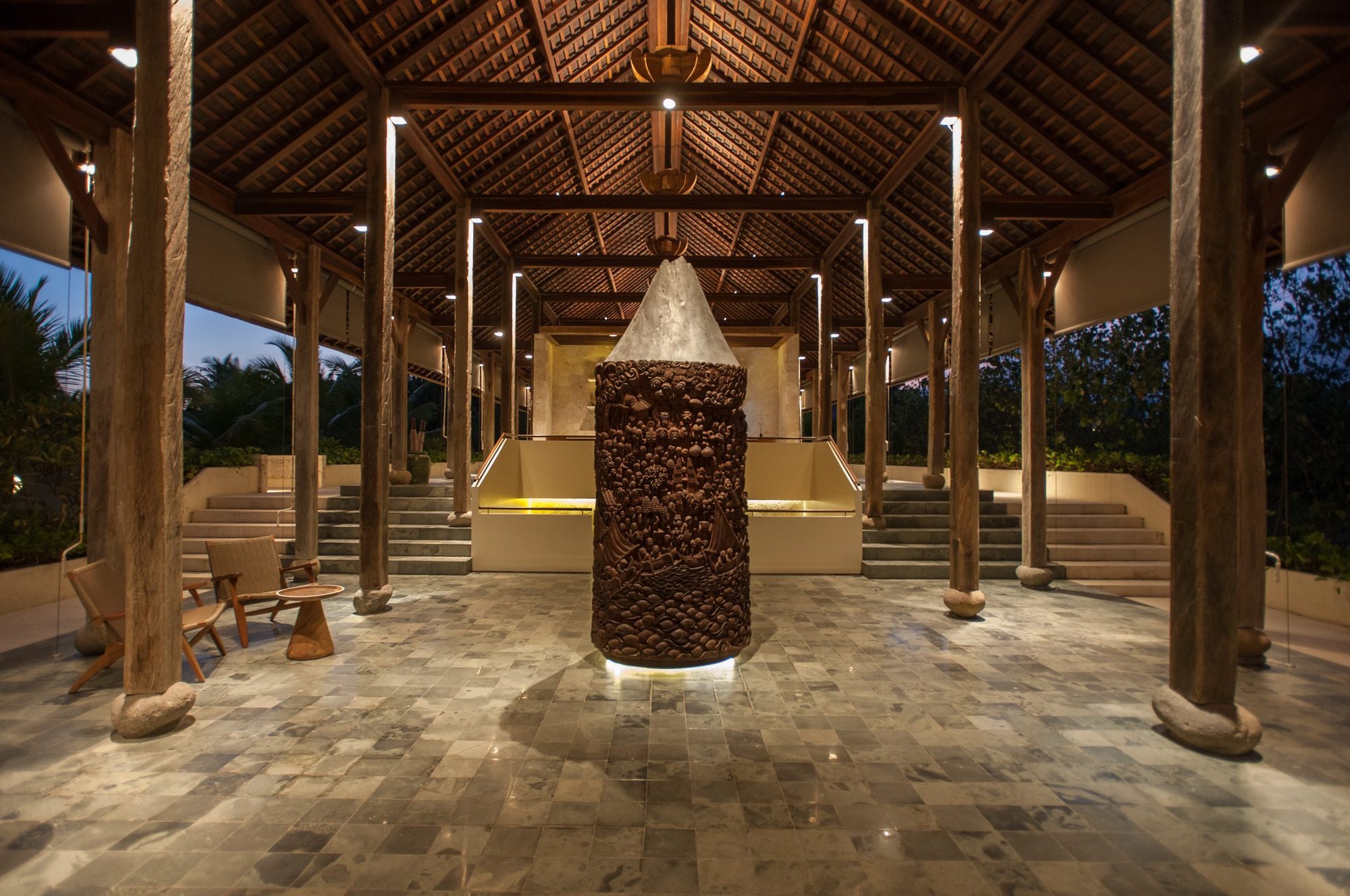 The lobby at Komaneka at Keramas Beach at dusk, with a carved wooden sculpture of Mount Agung