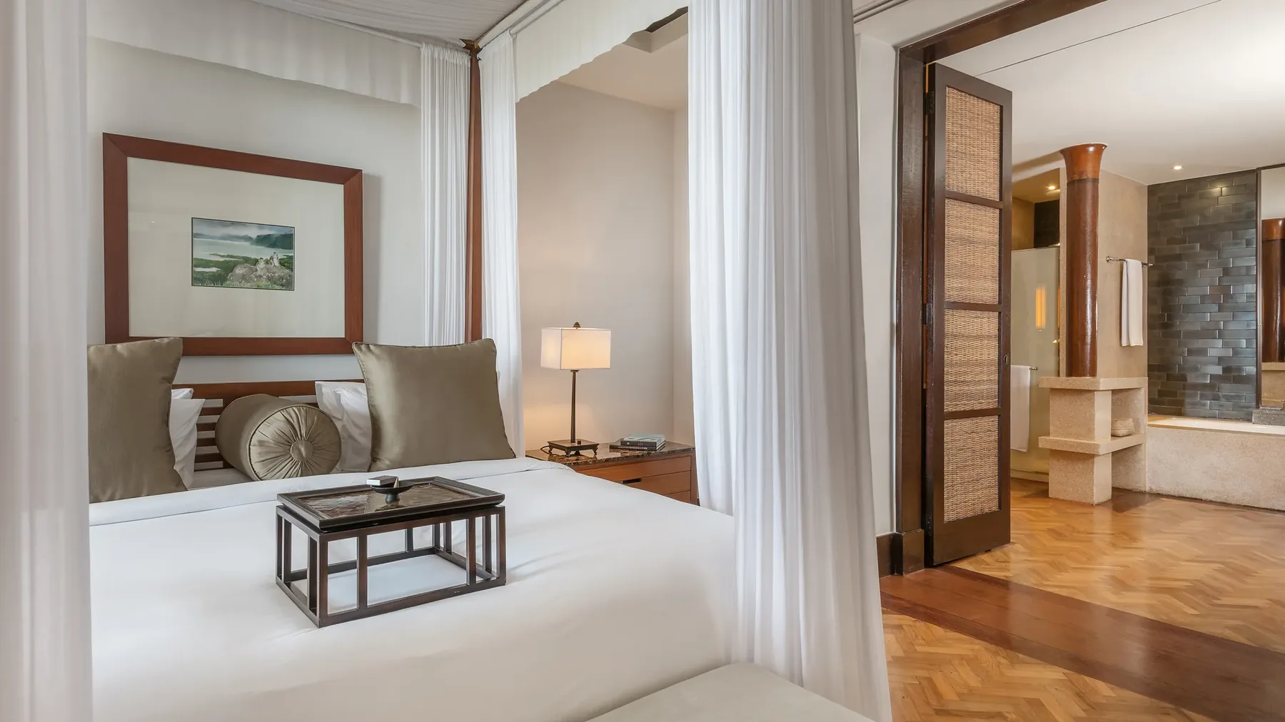 A four-poster suite bedroom at The Legian, with the bathroom beyond
