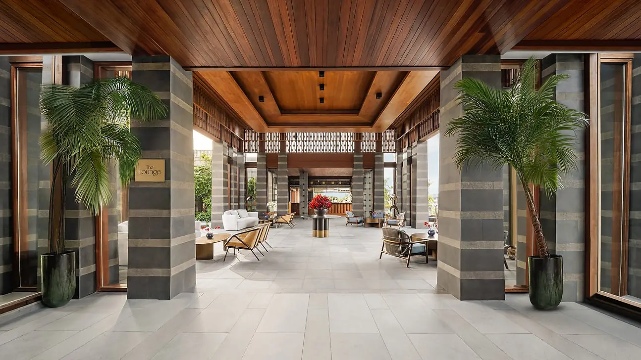 The Lounge at Regent Bali Canggu, a colonnaded arrival corridor with palm trees either side