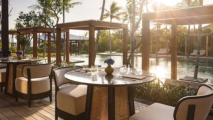 Poolside dining tables at Regent Bali Canggu at golden hour