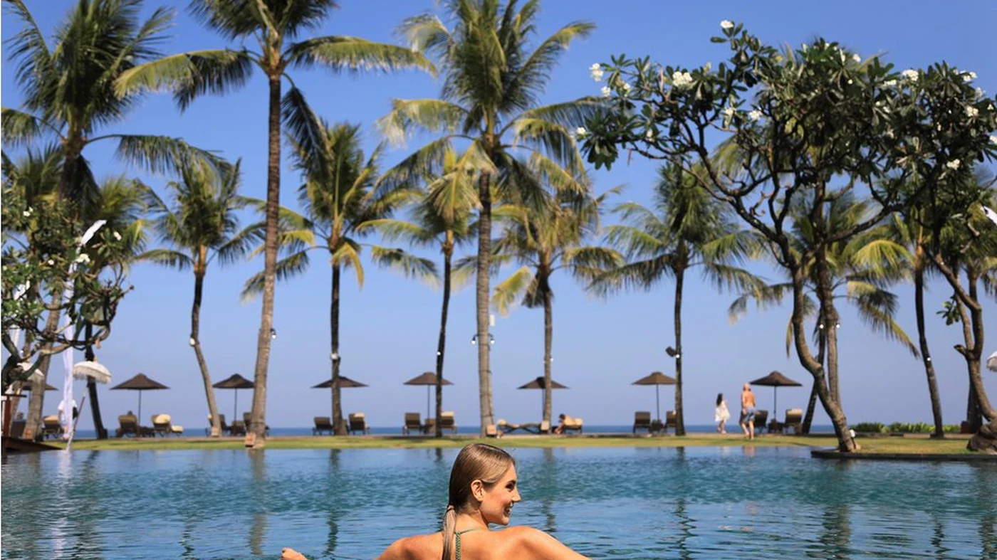 Swimming in the main pool at The Samaya Seminyak, palms along the beach beyond