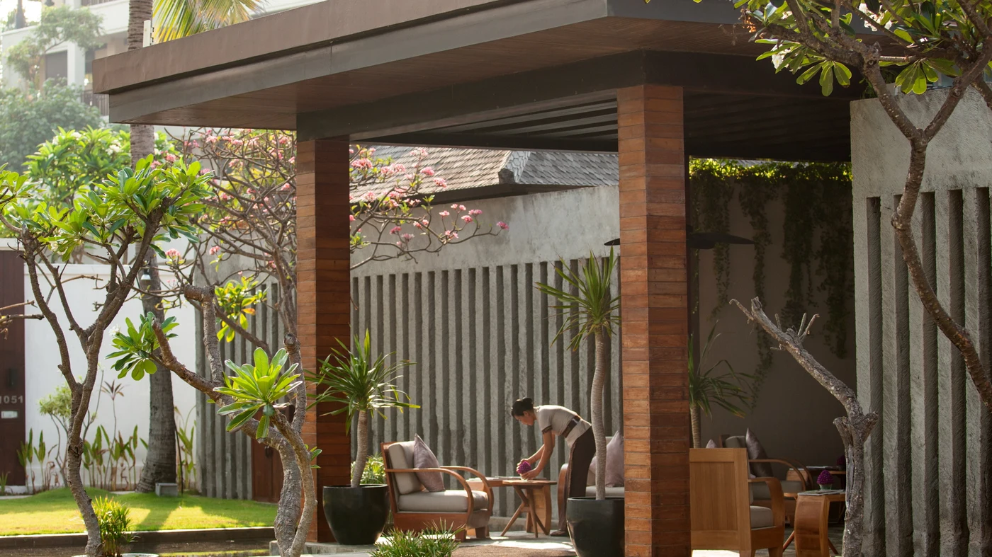 A staff member arranging flowers in a garden pavilion at The Samaya Seminyak