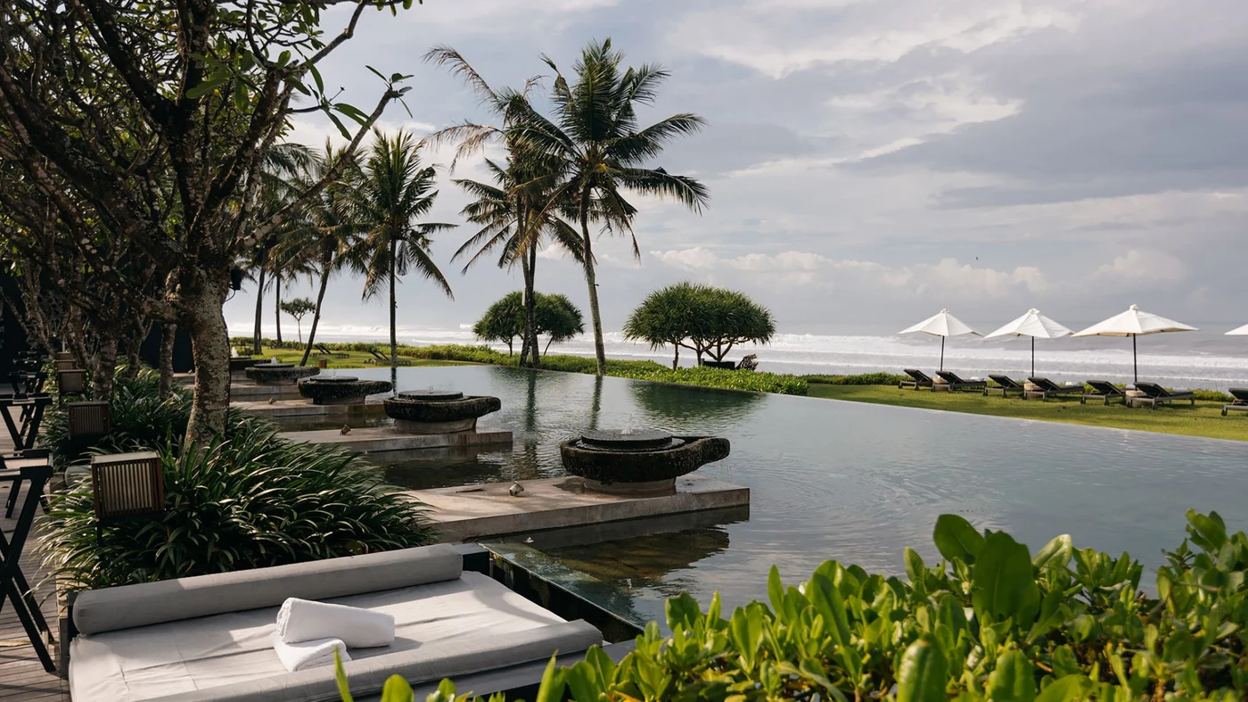 A daybed and folded towel beside the pool at Soori Bali