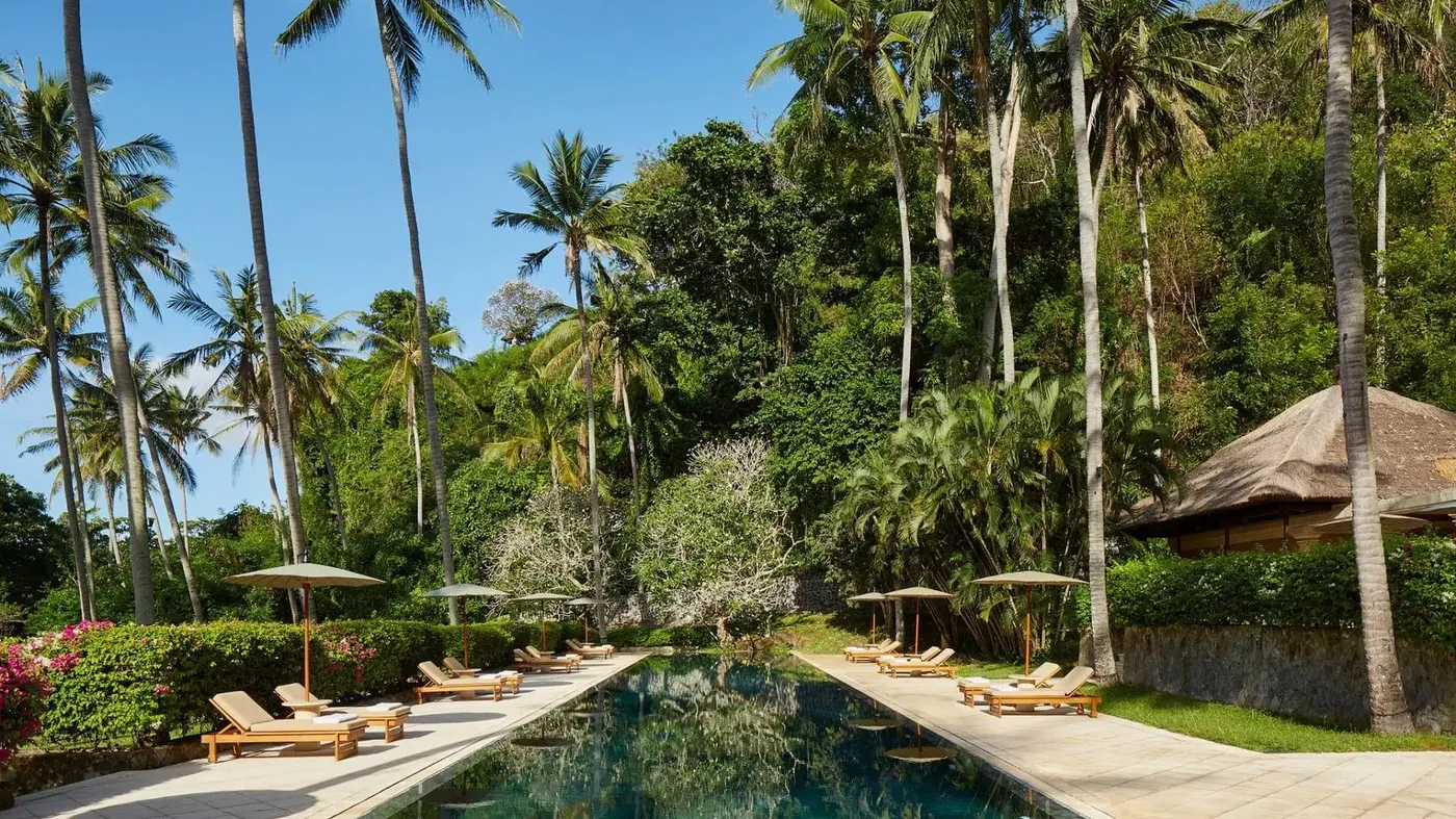 The quiet pool at Amankila's Beach Club, flanked by tall palm trees