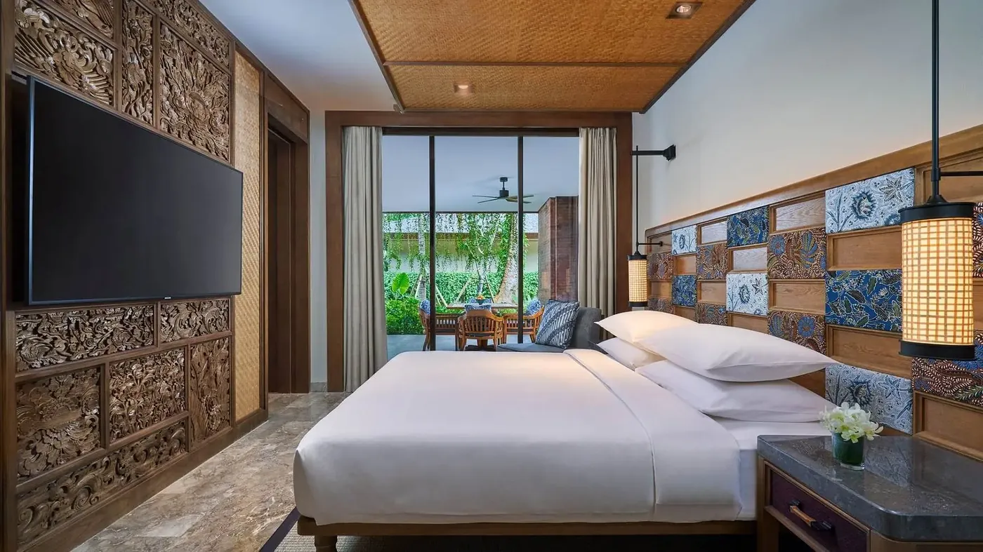 A bedroom at Andaz Bali with carved wood panelling and batik tile detailing