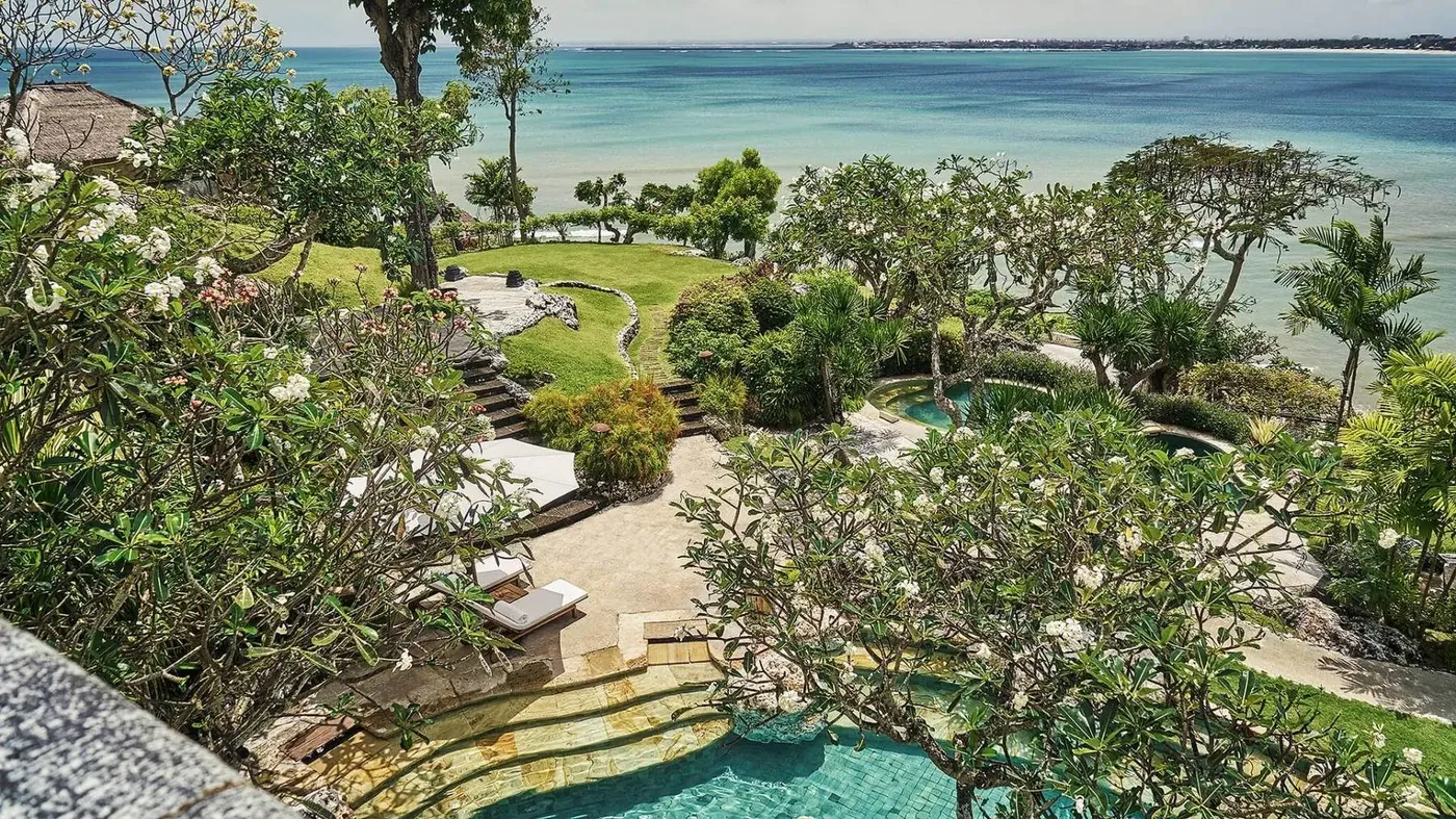 Aerial view of the gardens and pools at Four Seasons Resort Bali at Jimbaran Bay, framed by frangipani trees