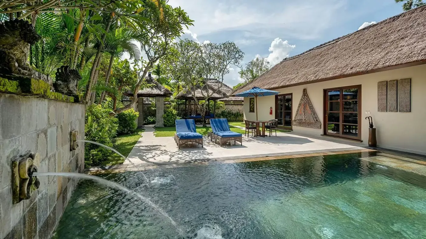 A private pool villa at Jimbaran Puri, with sun loungers, a blue umbrella, and a plunge pool