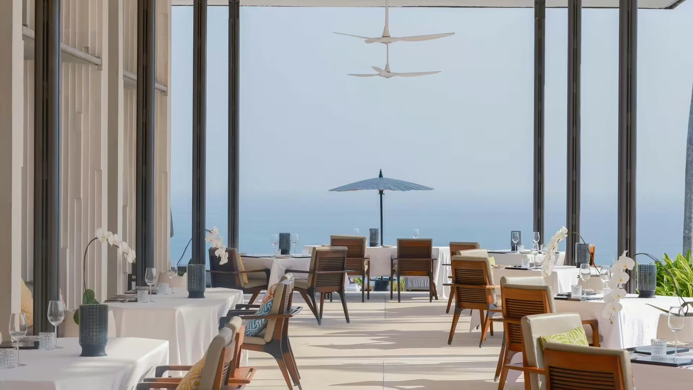 The empty terrace at CIRE, Alila Villas Uluwatu's cliff-edge restaurant, set for dinner with the ocean beyond
