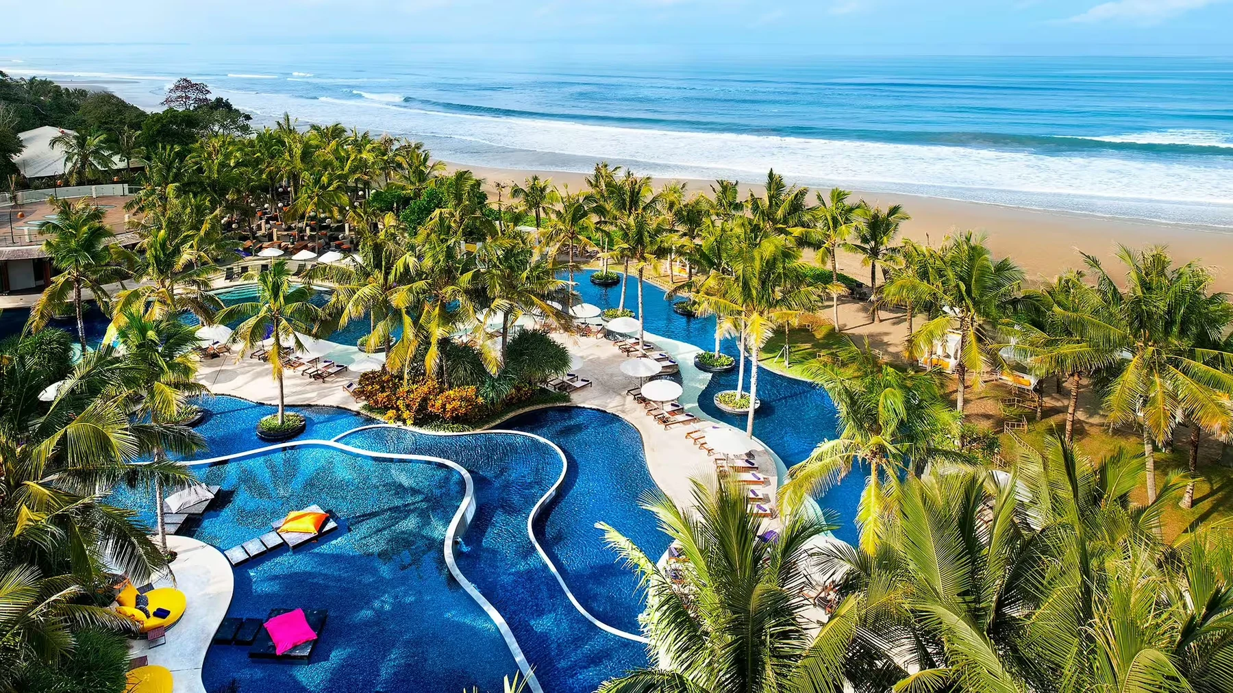 The winding pool at W Bali, Seminyak, palm trees leading down to the beach